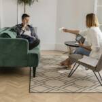 Upset young man getting divorced, sitting on couch in counselor's office, touching his face,